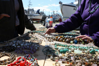Dannielle Carbone points out a semiprecious stone to explain to customers what they are and where they come from. She set up shop this June at her boat in Dillingham's PAF boatyard. (Photo by Austin Fast/KDLG)