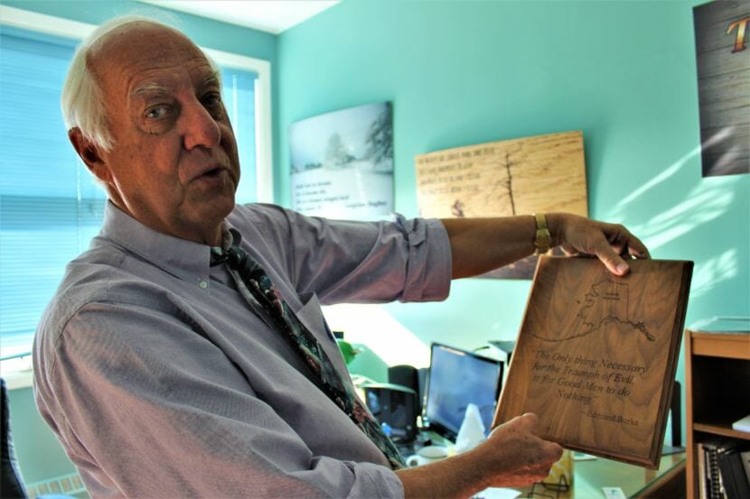 Outgoing Juneau Mayor Ken Koelsch holds up a wooden plaque featuring a quote by political theorist Edmund Burke. (Photo by Adelyn Baxter/KTOO)