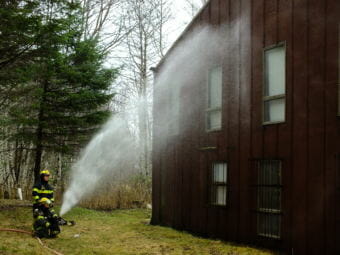 Steam billows off the side of a nearby building as Capital City Fire/Rescue firefighters hose it down to prevent it from catching fire as the adjacent Thane Ore House burns on Nov. 24, 2018.