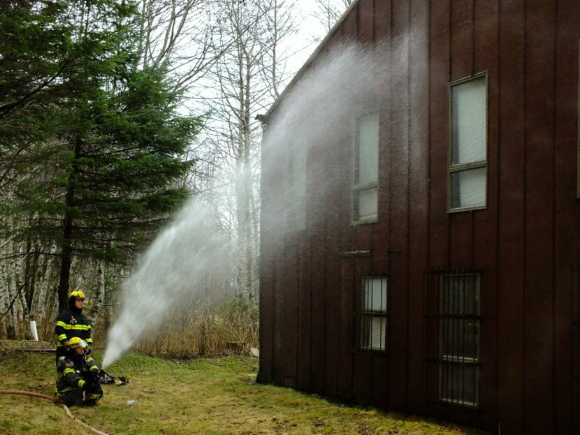 Steam billows off the side of a nearby building as Capital City Fire/Rescue firefighters hose it down to prevent it from catching fire as the adjacent Thane Ore House burns on Nov. 24, 2018.