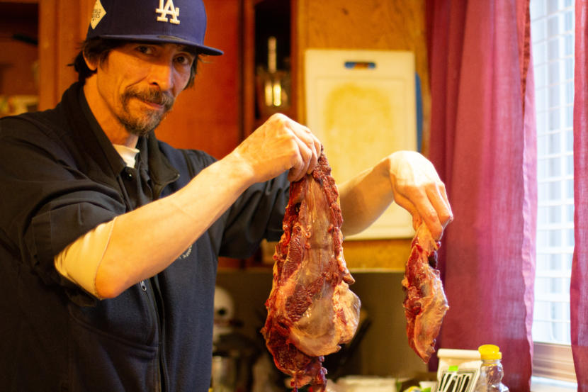 Robert Melovidov holds up fur seal meat that he’s preparing to cook in his home on St. Paul island in January. Unangan people on St. Paul like Melovidov have been pushing the federal government for more than a decade for more freedom to harvest the fur seals they share the island with.