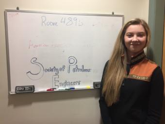 Sydney Deering stands next to a whiteboard with the words "Society of Petroleum Engineers" written on it.