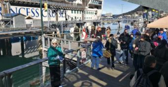 Vicki Logan of Travel Juneau greets and hands out walking maps to passengers of the Ruby Princess at the Franklin Dock on Sunday, April 28, 2019. (Photo by Jeremy Hsieh/KTOO)