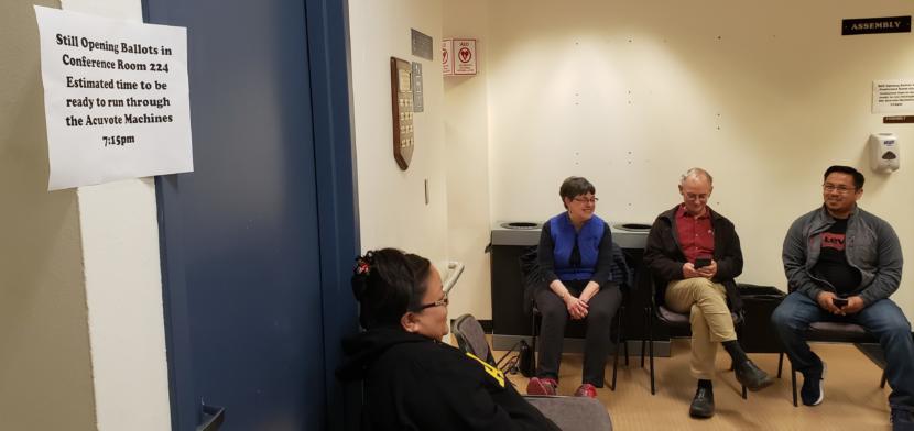 Ann Stepetin, Deedie Sorensen, Jeff Short and Martine Stepetin wait for a machine count of absentee and quesitoned ballots at Juneau City Hall on Friday, Oct. 4, 2019. Contrary to the sign, the machine count didn't begin until about 8:40 p.m.