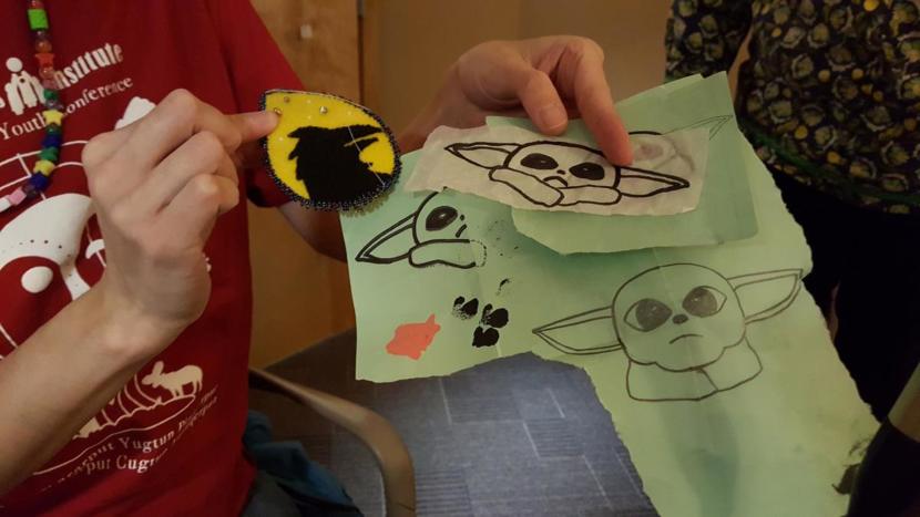 Gatgyedm Hana’ax Karla Booth (Ts’msyen) shows off a beading project and sketches she made in preparation to make a Baby Yoda Christmas tree ornament that she gifted. (Photo by Tripp J Crouse/KNBA)