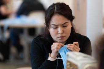 Dental Assistant Apprentice Mikayla Kassaiuli sews a mask for medical providers in case protective gear runs out during the COVID-19 outbreak. March 26, 2020 in Bethel. (Katy Basile / KYUK)