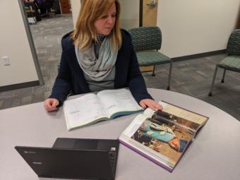 Jennifer Knutson, the senior director of teaching and learning for the Anchorage School District, shows some textbooks and a district-issue Chromebook that students have access to on March 13, 2020. She says that there will need to be a combination of traditional and e-learning opportunities for students during school closure. (Photo by Mayowa Aina/Alaska Public Media)