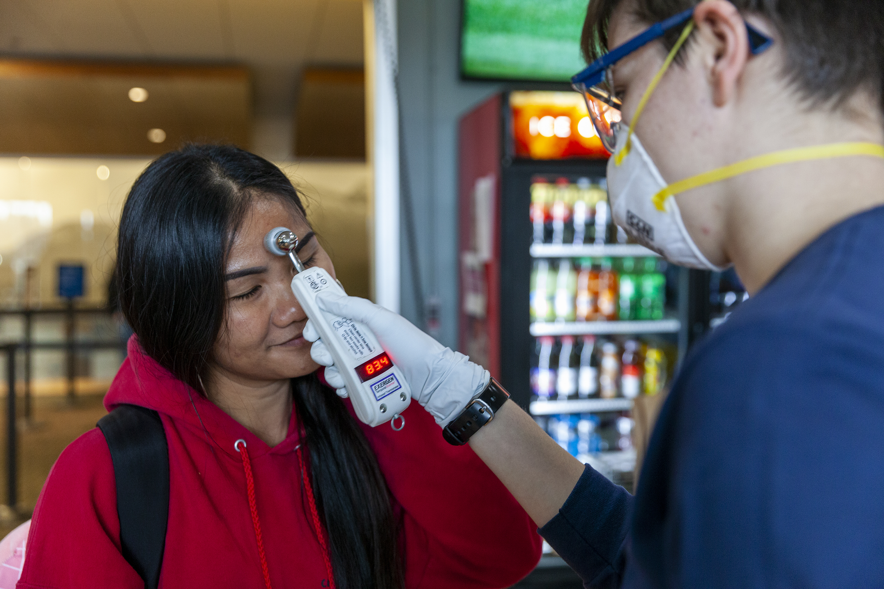 Namfon Noisai gets her temperature checked by Capital City Fire/Rescue's Lily Kincaid during a voluntary screening at Juneau International Airport on Saturday, March 21, 2020 in Juneau, Alaska.