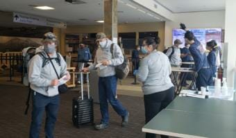 Screeners working for Capital City Fire/Rescue check paperwork and go through out-of-state travelers' options and obligations to fulfill COVID-19 health mandates at Juneau International Airport on June 26, 2020.