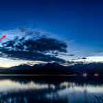 Panoramic composite photo from north Douglas at about 12:40 am on Thursday July 16, 2020. The comet C/2020 F3 (NEOWISE) "NEOWISE" is visible among noctiluminescent clouds just above and to the left of the darker clouds, as indicated by the red arrow. Image has been adjusted to enhance contrast. (Photo by Mikko Wilson/KTOO)