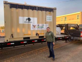Melissa Berns-Svoboda stands in front of one of the shipping containers the bulls traveled in. She checked on them regularly throughout their journey to Alaska and said them seemed to handle the ride OK. (Photo courtesy of the Old Harbor Alliance)