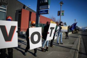 Volunteers and organizers with the Alaska Civic Engagement State (AKCES) Table gather on Election Day 2020 in Mountain View to remind residents to vote. AKCES is a nonpartisan group with 75 volunteers that have been showing up at the polls to support voter education and safety. (Jeff Chen/Alaska Public Media)