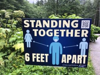 A sign that says "Standing Together 6 Feet Apart"