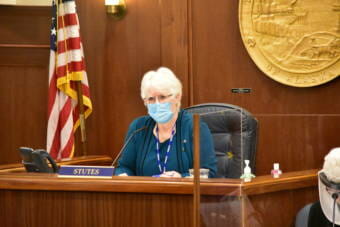 Photo of Alaska House Speaker Louise Stutes as she sits at her bench. She is wearing a disposable facemask and is looking into the House gallery.