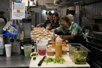 Aims Villanueva-Alf adds root vegetable toppings to pancit, a dish she prepared for In Bocca Al Lupo's event "Dinner with Friends: Womxn of Power edition" on June 26 in Juneau, Alaska. The event highlighted four women chefs of color, three local chefs and one from San Diego. (Photo by Lyndsey Brollini/KTOO)