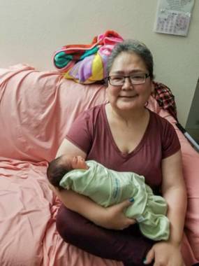 A woman sitting on a couch holding an infant