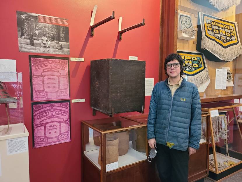 Zachary James standing by one of his museum displays of infrared images of formline paintings
