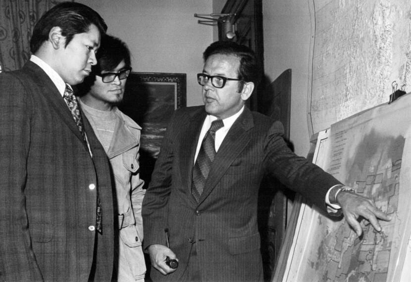 A black-and-white photo of three men studying a map