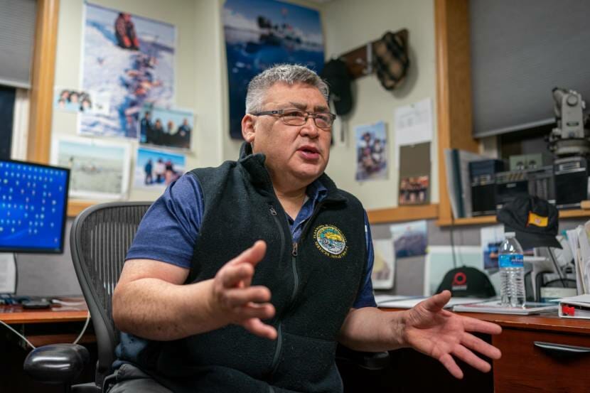 A man sitting at his desk, gesturing as he speaks