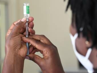 A nurse drawing vaccine from a bottle with a syringe