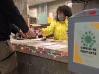 A woman hands a test to someone over a counter