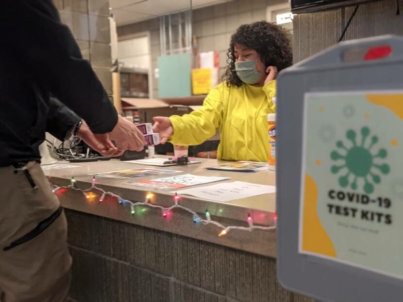 A woman hands a test to someone over a counter