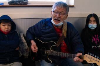 A man playing guitar in an airport waiting area