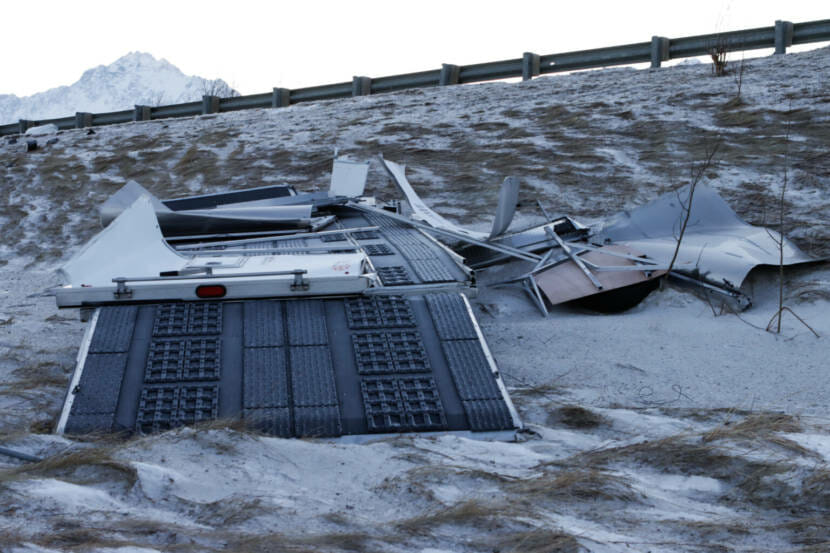A flattened cargo trailer lying by the road.