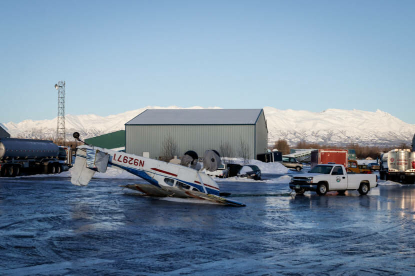 A single engine plane lying upside-down at a small airport