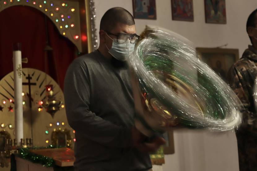 A man in a church spinning a tinsel star, which appears green in the middle