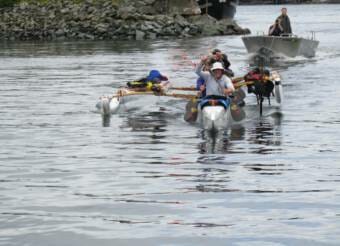 Paddlers in an outrigger canoe followed by a skiff