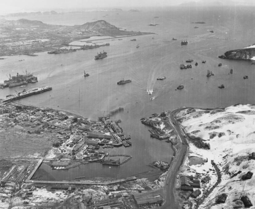 A black-and-white aerial photo of a naval base in the Aleutians, with many ships in the harbor.