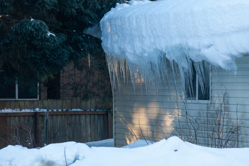 A very thick slab of snow on top of a house’s roof