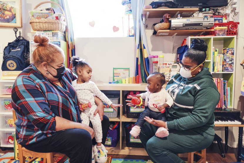Two women in side a day care holding children on their laps