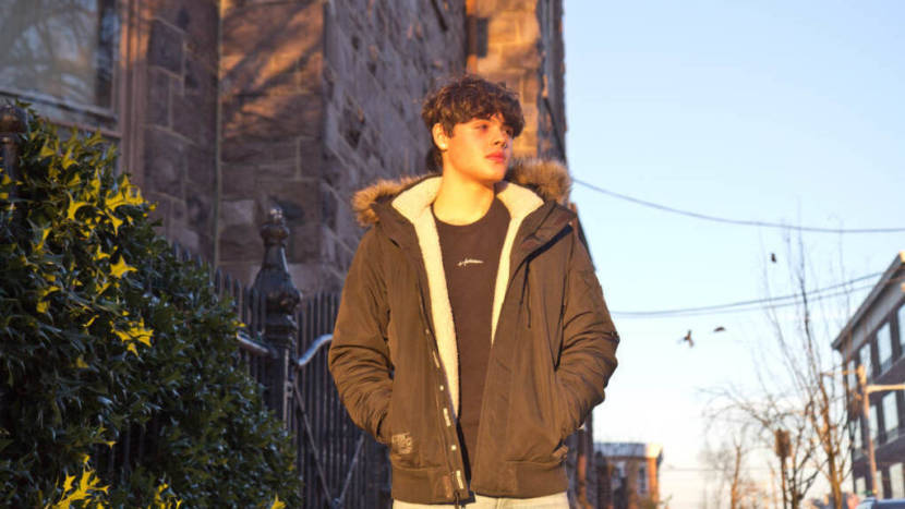 A portrait of a young man walking down a city street