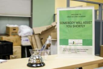 A sign by an unstaffed counter that says "someone will assist you shortly"