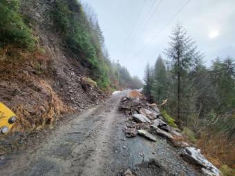 A gravel road with piles of rock along the side after a landslide was cleared