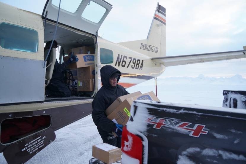 A man unloading boxes from an airplane into the bed of a pickup