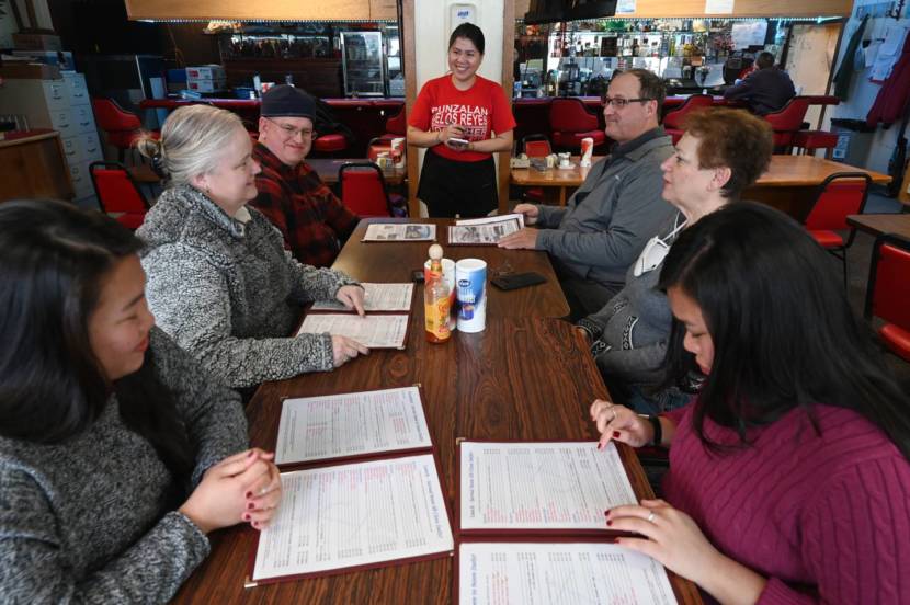 People sitting around a restaurant table, looking at menus