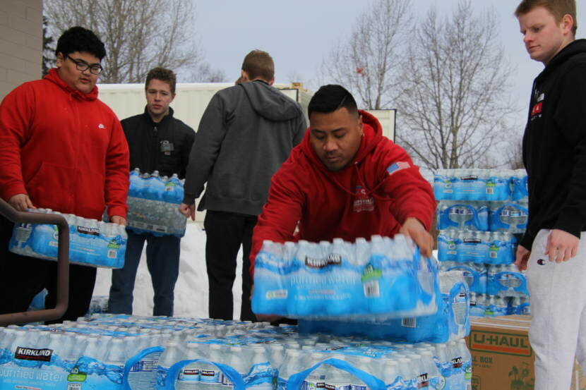 Men stack up cases of bottled water outside