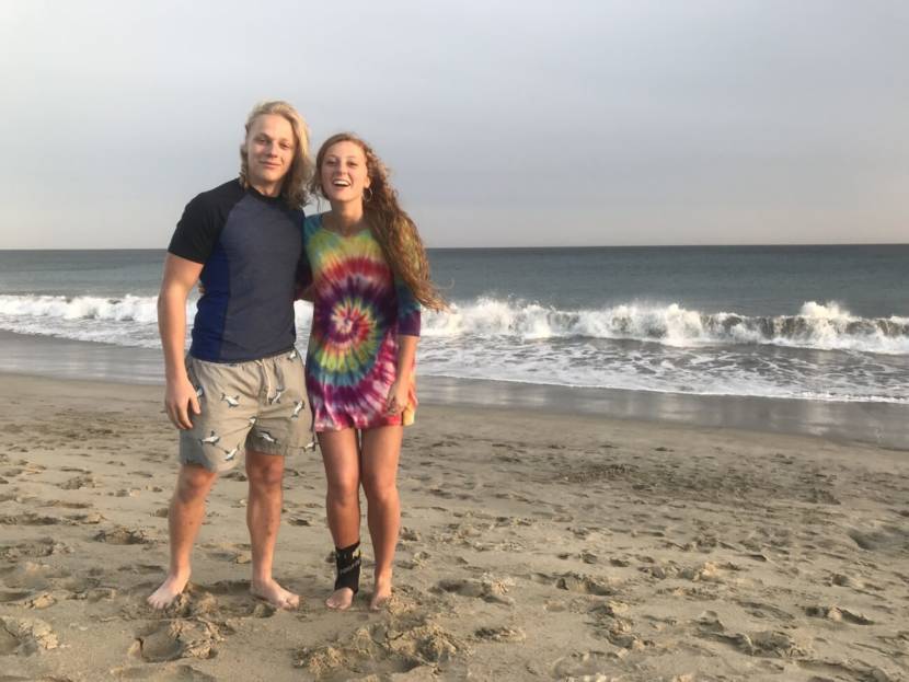 A young man and women standing on a beach, smiling