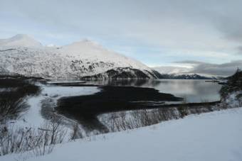 A narrow bay in winter with mountains across the water