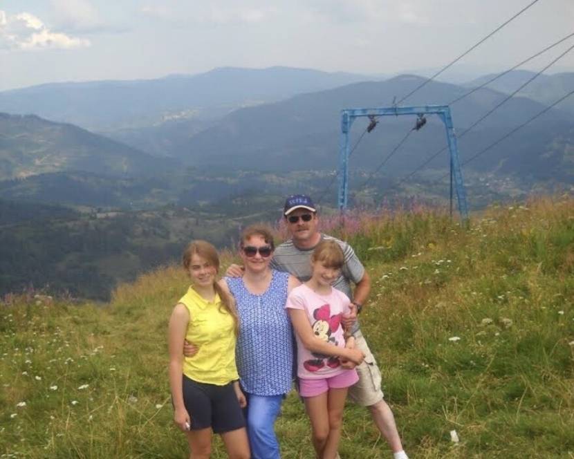 A family of four poses for a photo in the mountains