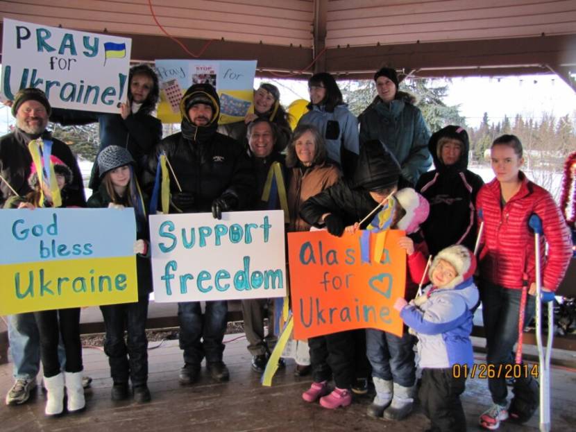A group photo of people holding protest signs with slogans like "God Bless Ukraine" and "Support freedom."