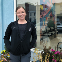 A portrait of a young woman standing in front of a shop window