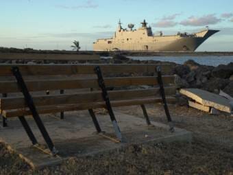 A very large military ship docked at a long wharf