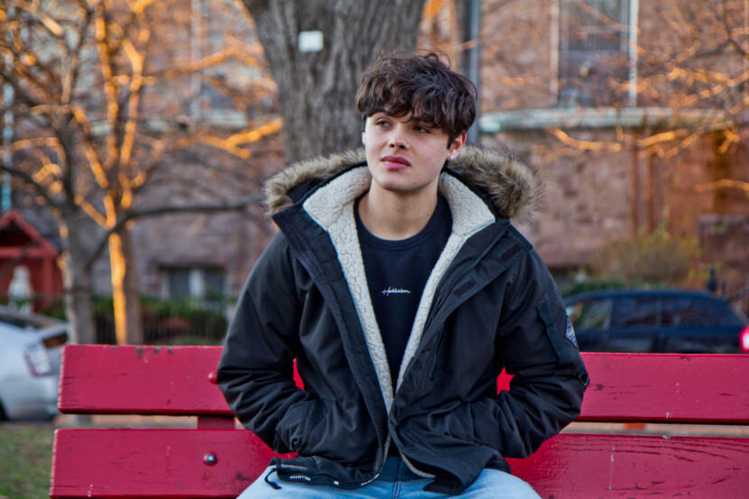A young man sitting on a red park bench