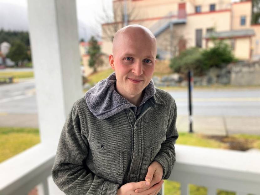 A portrait of Jonathan Kreiss-Tomkins standing on a porch