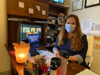 A masked woman sitting at an office desk