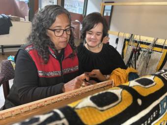 Two women weaving a blanket